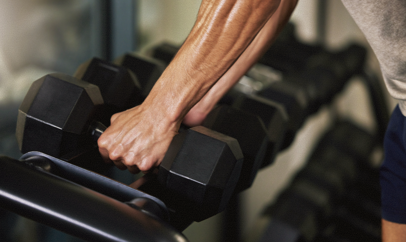 Member selecting a dumbbell from a weight rack